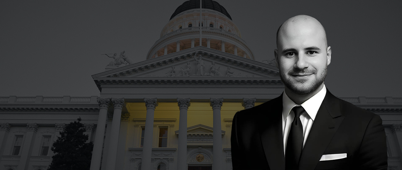 Black and white portrait of Attorney James L. Arrasmith in a suit in front of a domed government building with a yellow-lit base.