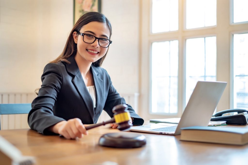  A focused legal secretary arranging paperwork and case files at her desk in a well-lit, contemporary California law firm